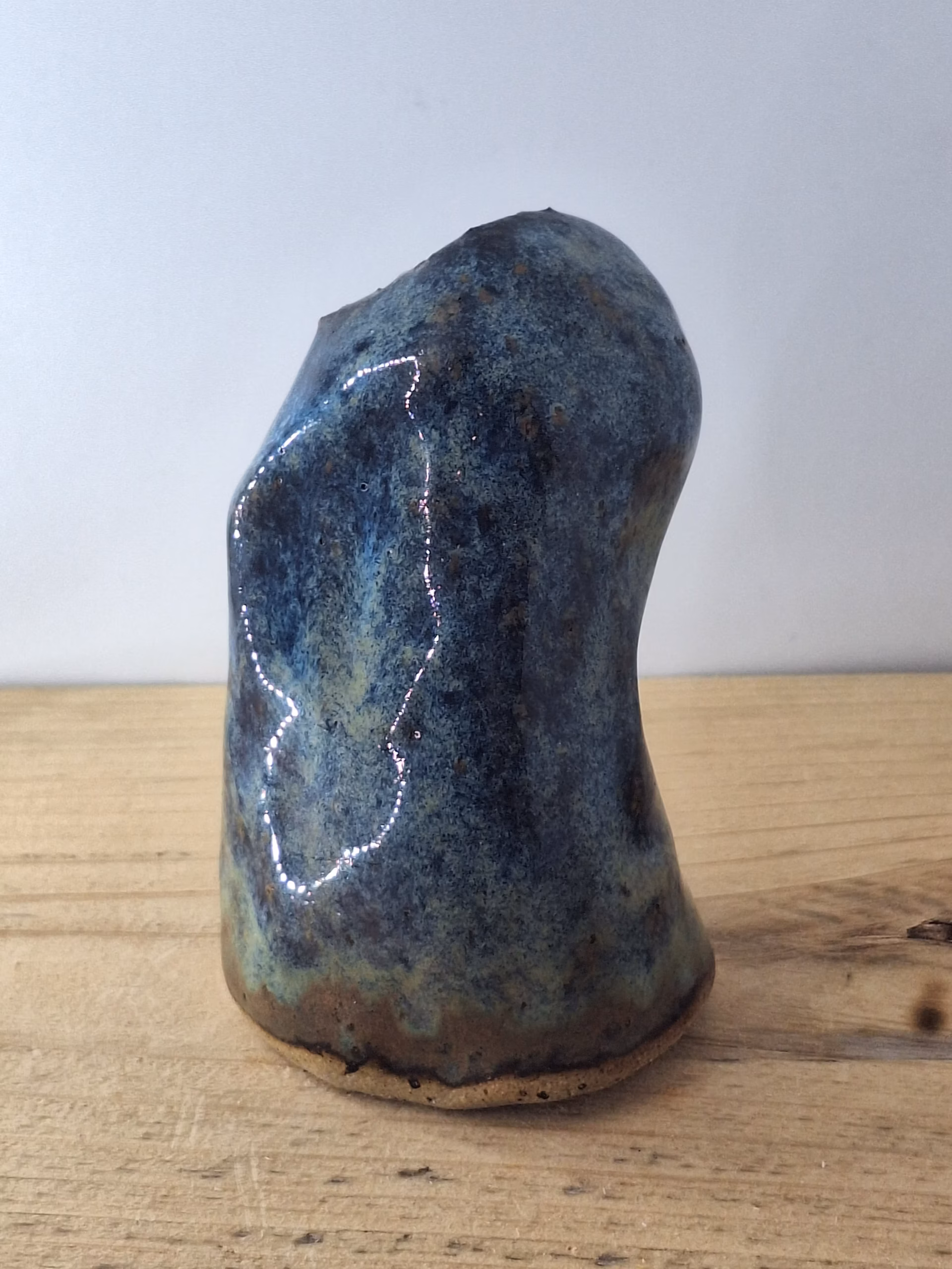 Small ceramic owlet with round head, dark hollow eyes, painted beak and feather detail in blue and brown tones.