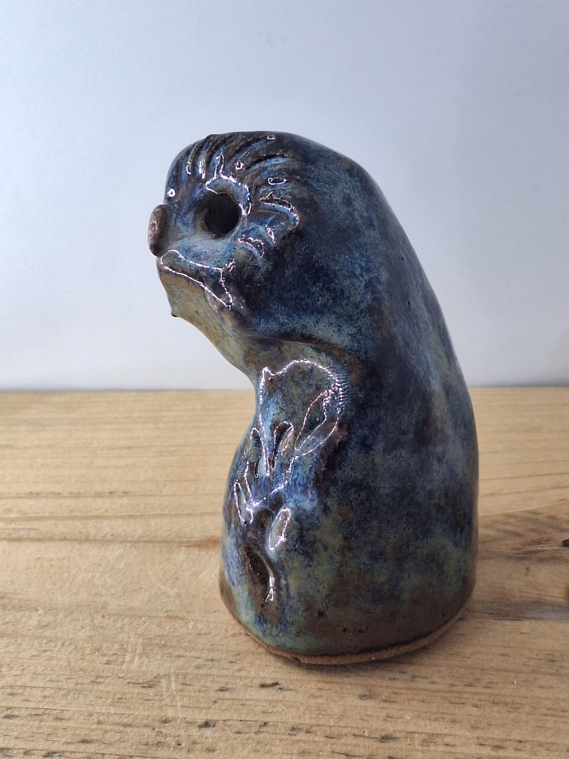 Small ceramic owlet with round head, dark hollow eyes, painted beak and feather detail in blue and brown tones.