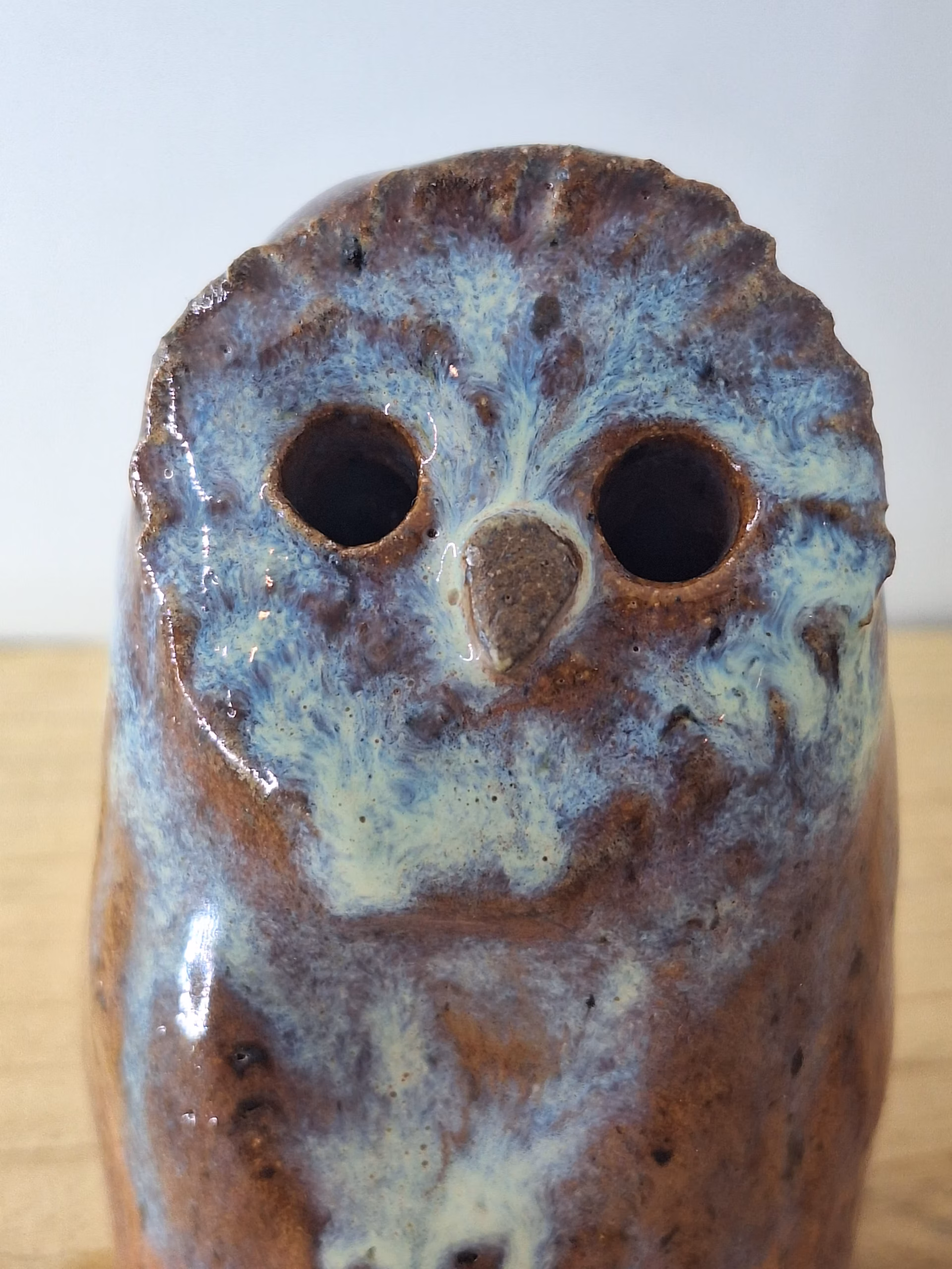 Small ceramic owl figurine with round body, large dark eyes, and mottled blue-brown painted surface.