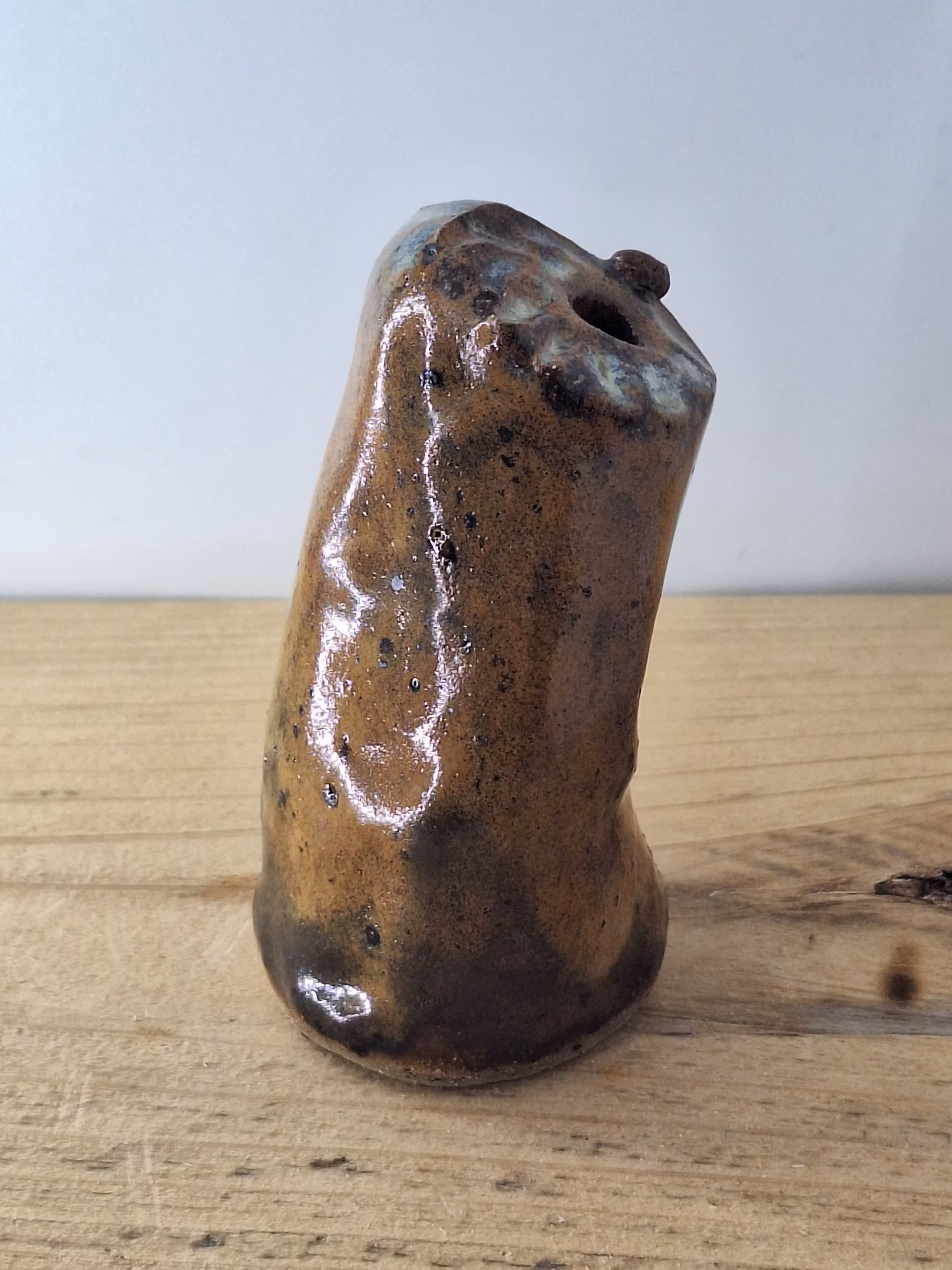 Small ceramic owl figurine with mottled brown and blue glaze, round head with large circular eyes and textured surface.