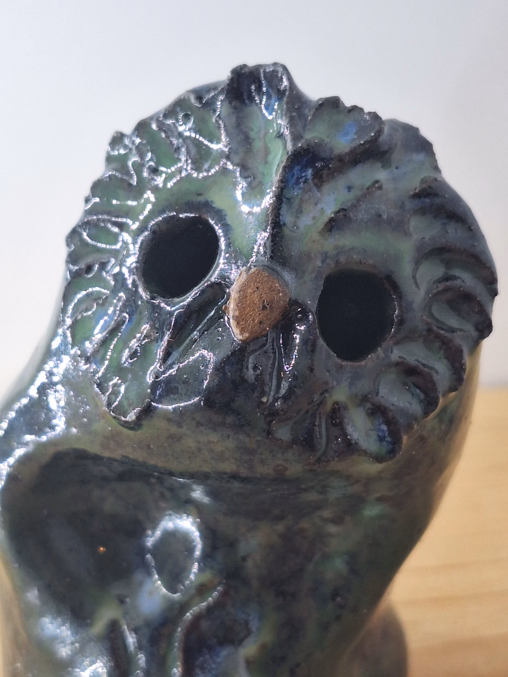 Small ceramic owl with dark glazed surface, white linear markings, and a copper-coloured bead for a nose.