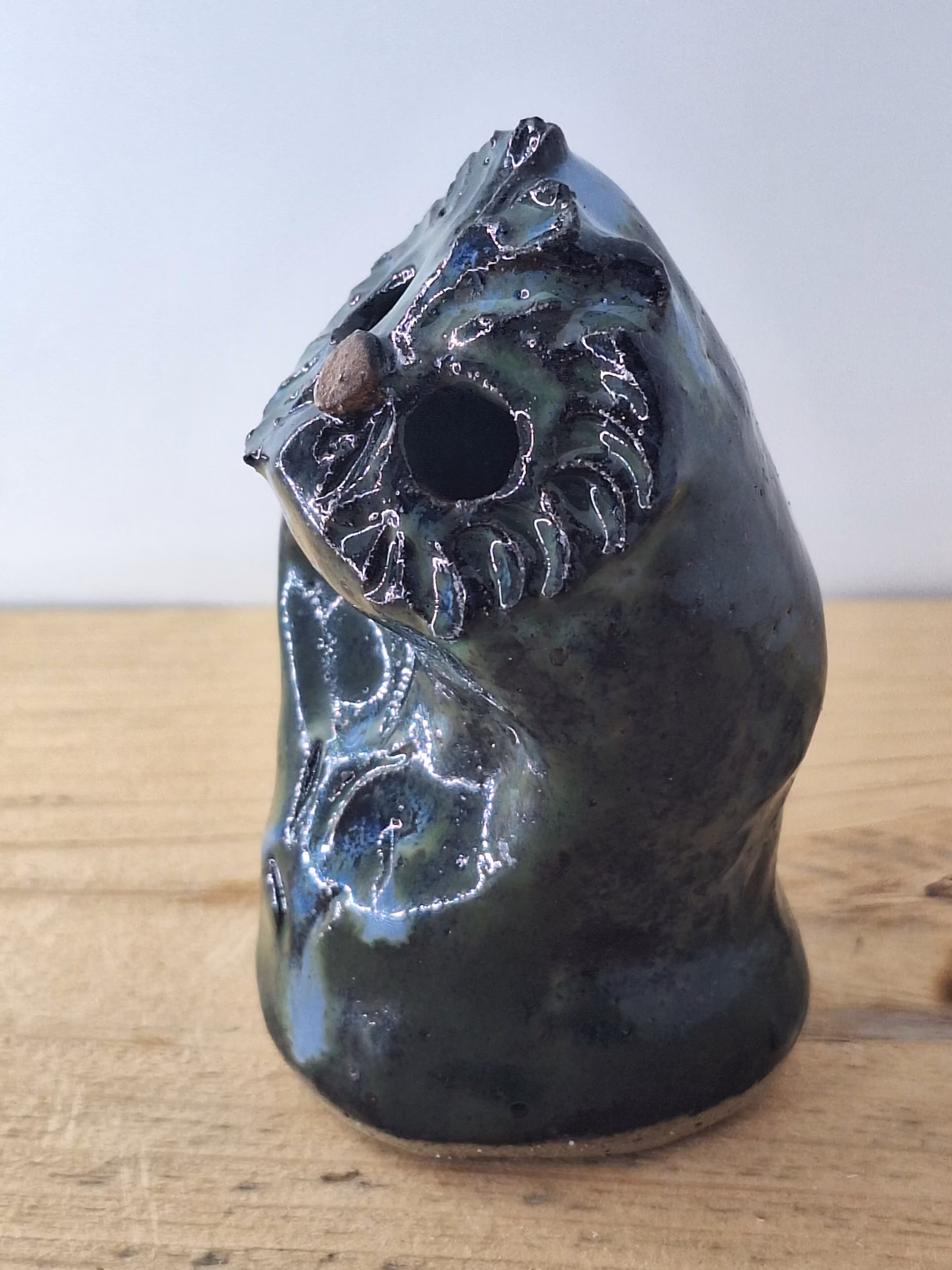 Small ceramic owl with dark glazed surface, white linear markings, and a copper-coloured bead for a nose.