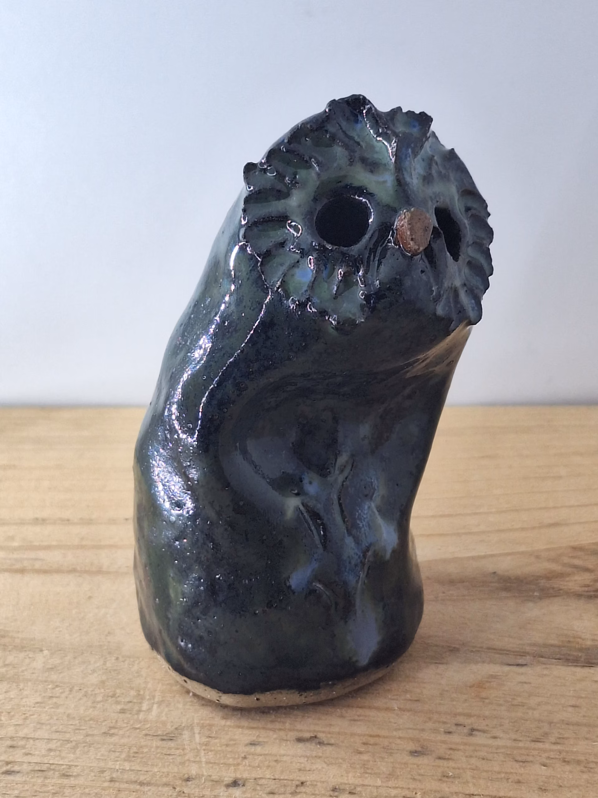 Small ceramic owl with dark glazed surface, white linear markings, and a copper-coloured bead for a nose.