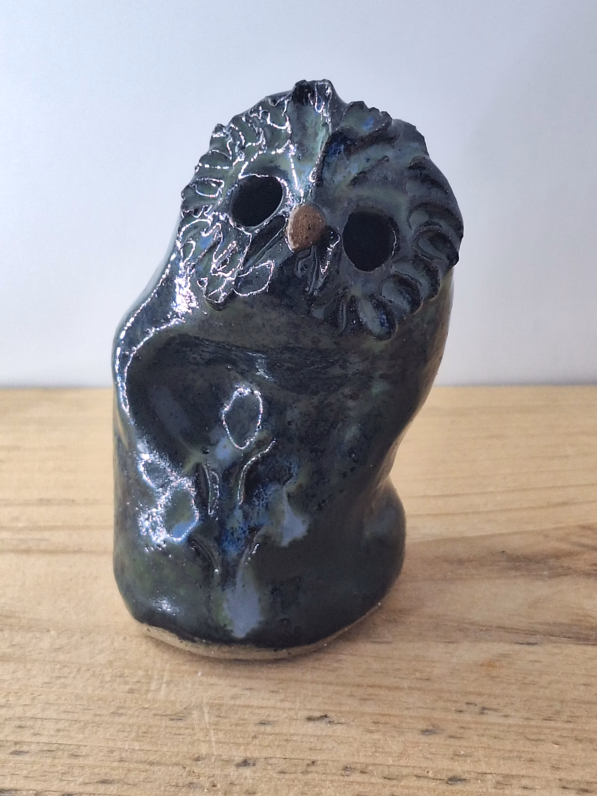 Small ceramic owl with dark glazed surface, white linear markings, and a copper-coloured bead for a nose.