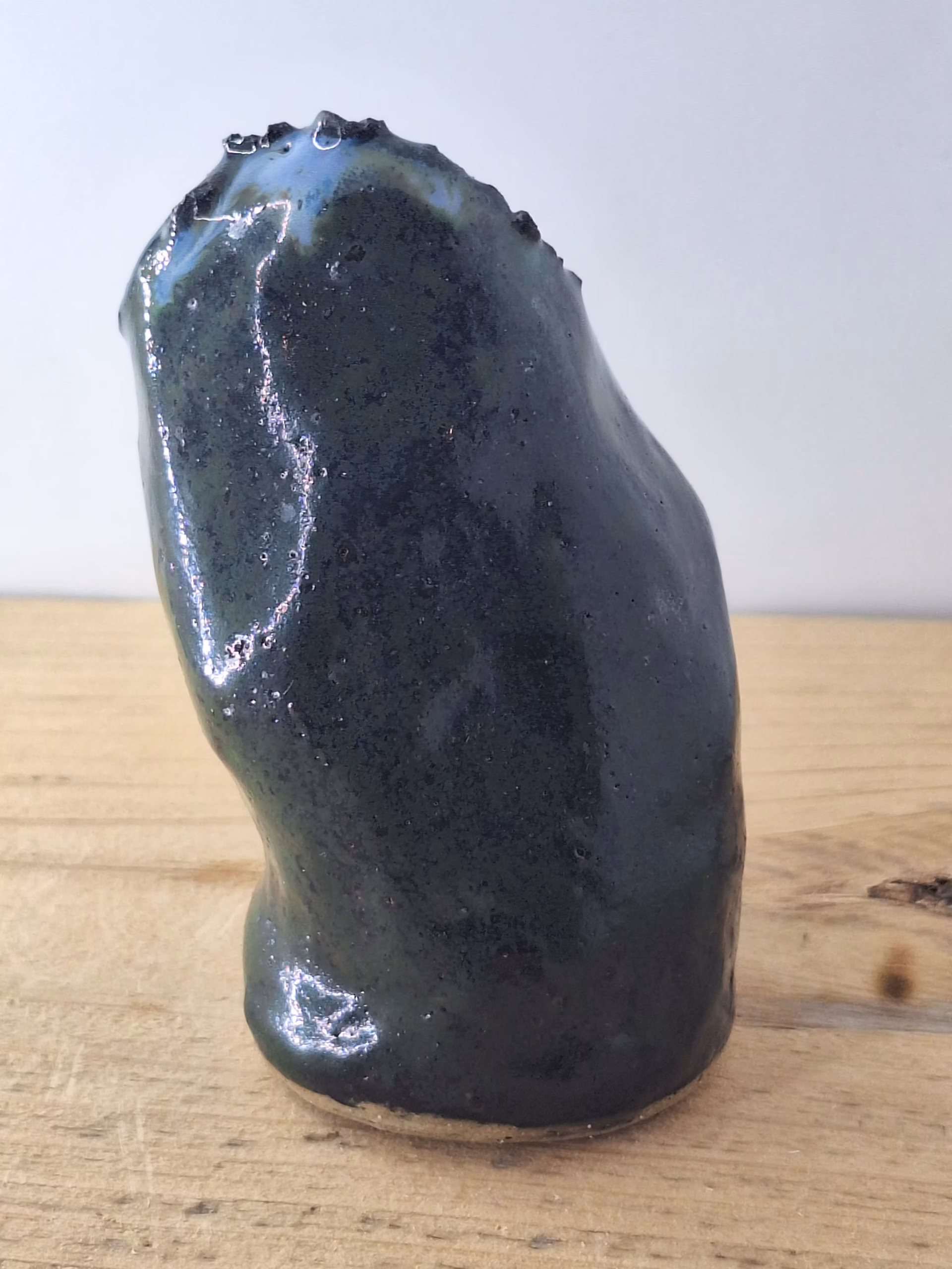 Small ceramic owl with dark glazed surface, white linear markings, and a copper-coloured bead for a nose.