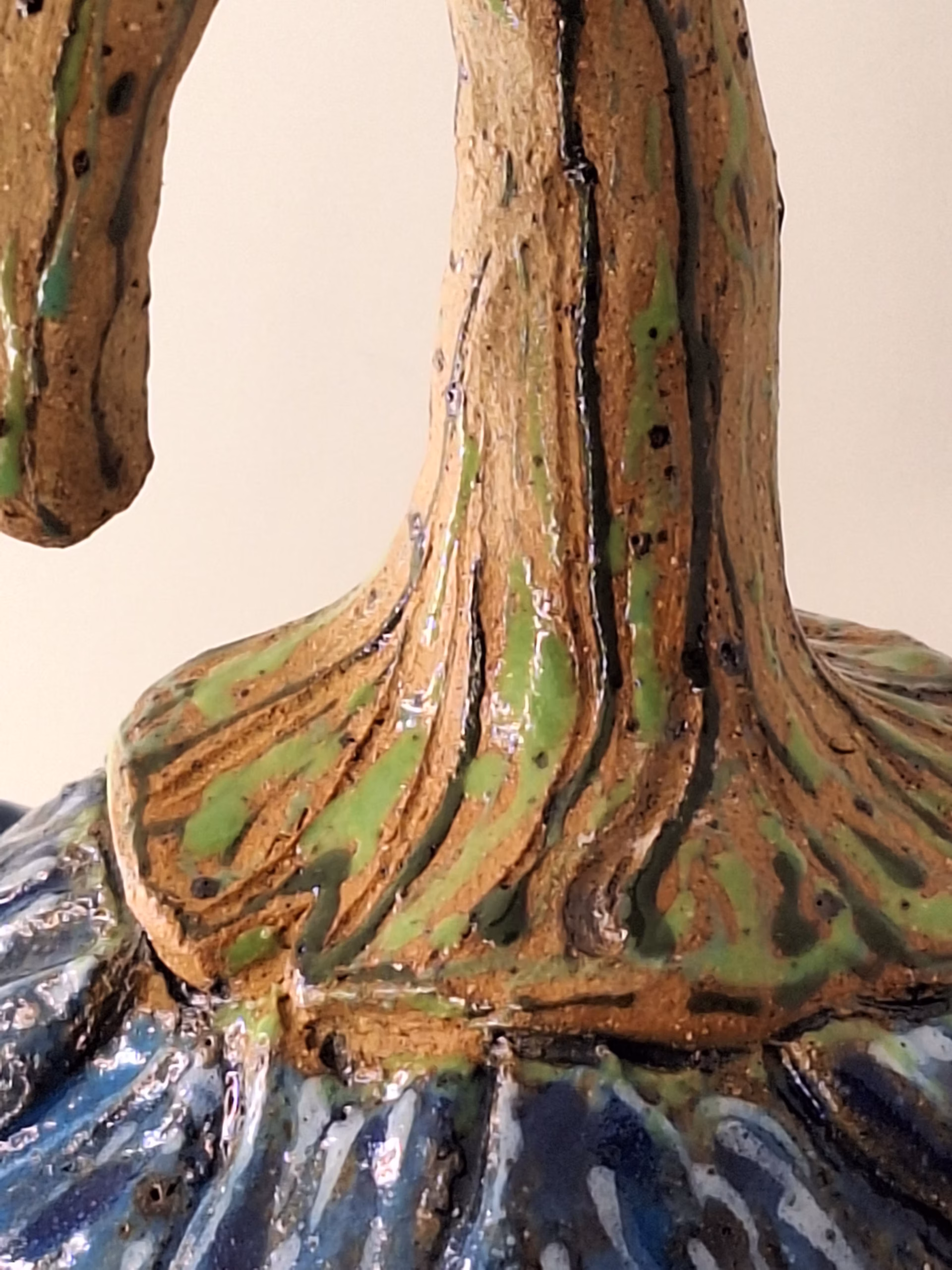 Small ceramic fairy house shaped like a bulbous acorn with deep wood-grain texture, deep blue draped fabric, curved hook stem, and a small heart-shaped door.