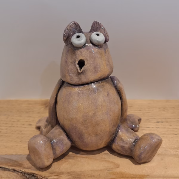 Oggbert the monster: a squat ceramic figure with a round belly, pointed ears, wide staring eyes and an open mouth, painted in warm earth tones.