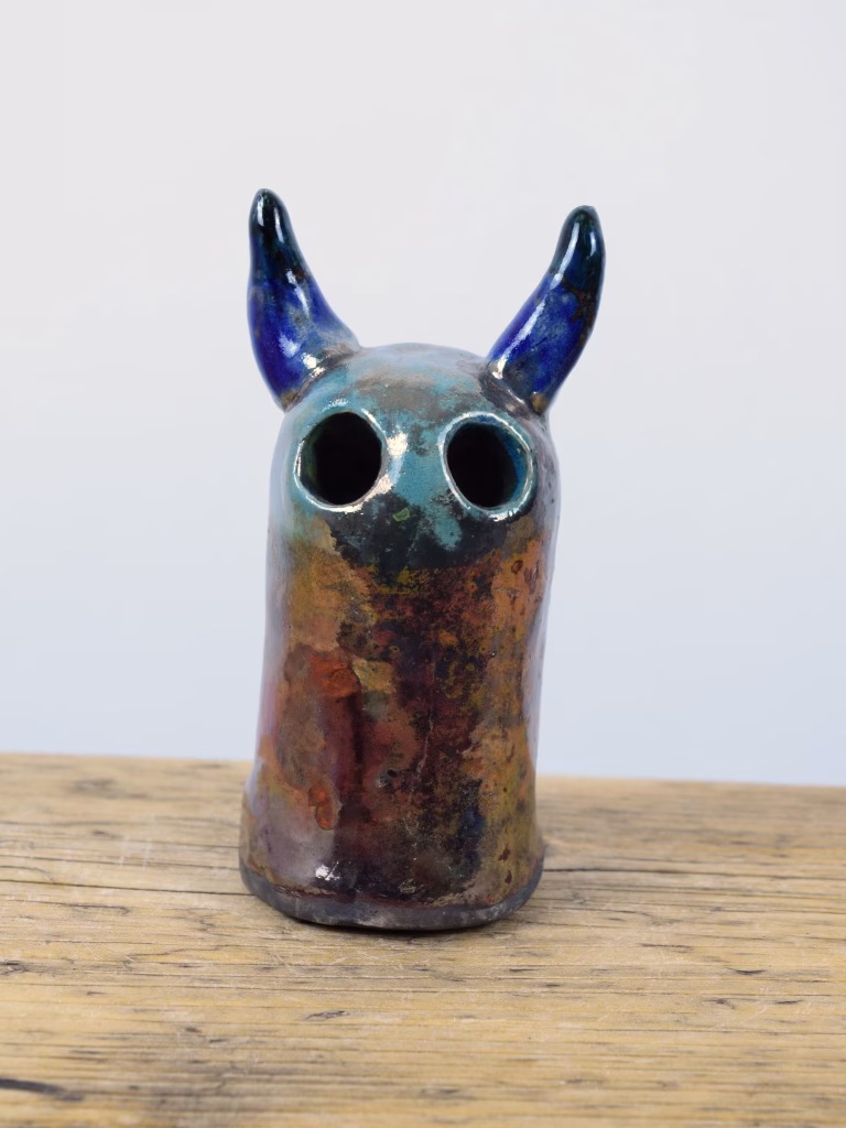 Raku Fire Demon, a small hand-built ceramic figure with glossy blue horns and a copper and teal raku-fired body