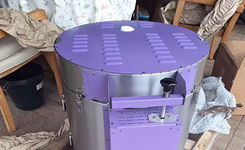 The new kiln unwrapped on its pallet: a steel drum with a purple lid and purple control box