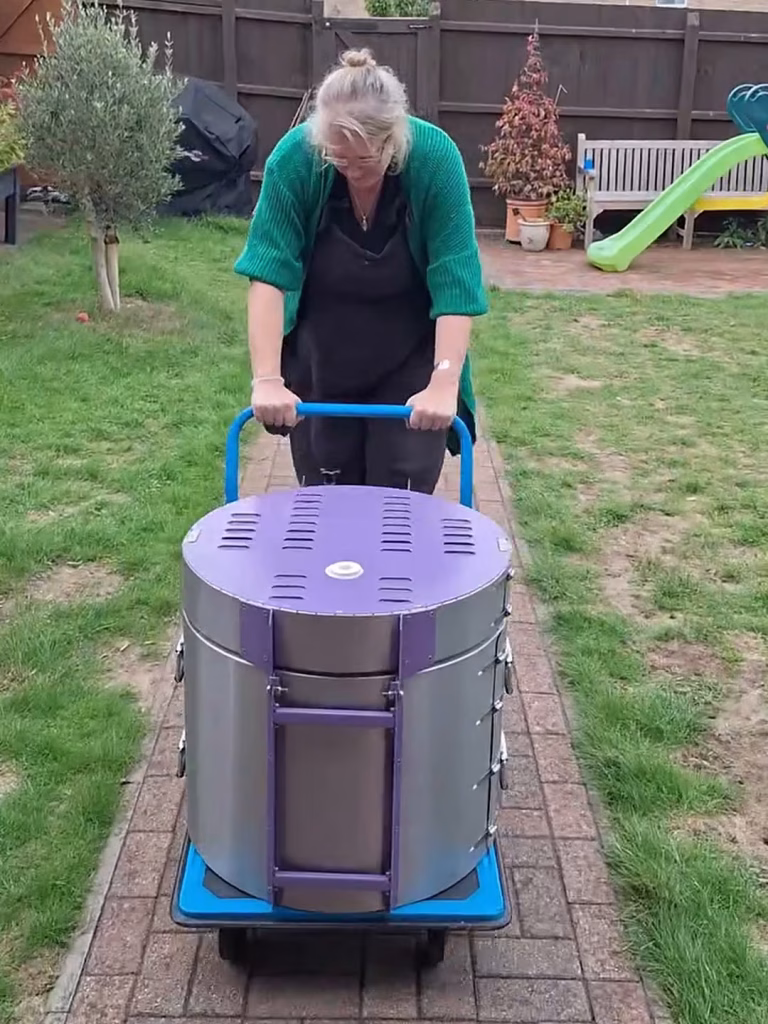 Briony pushing the kiln along the garden path on a blue trolley